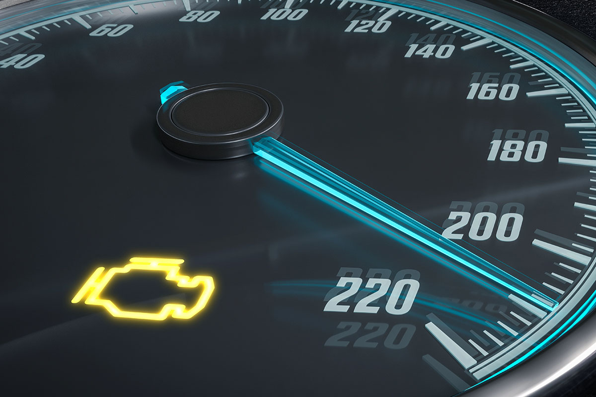 Close-up of a car speedometer displaying the needle just below 220 km/h, with a yellow engine warning light illuminated in the lower left.