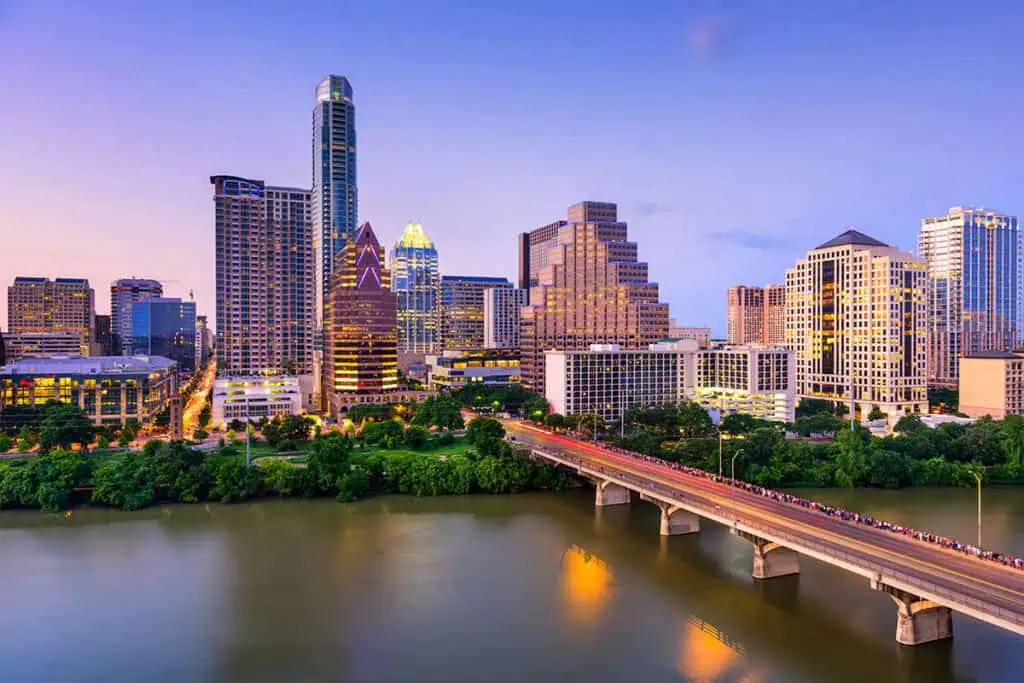 Austin city skyline with tall buildings and a river in the foreground.